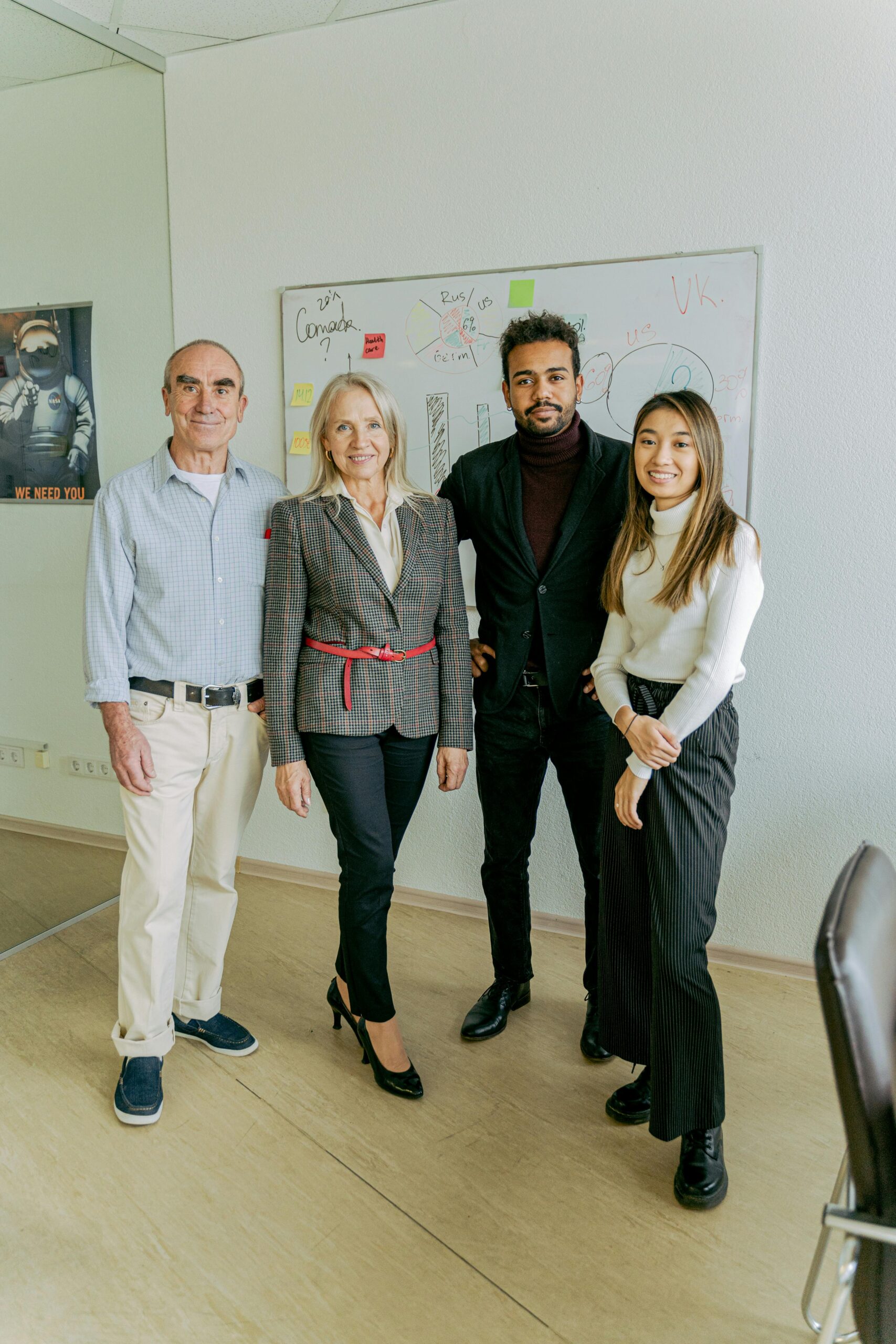 A diverse team of business professionals standing in an office with a whiteboard.
